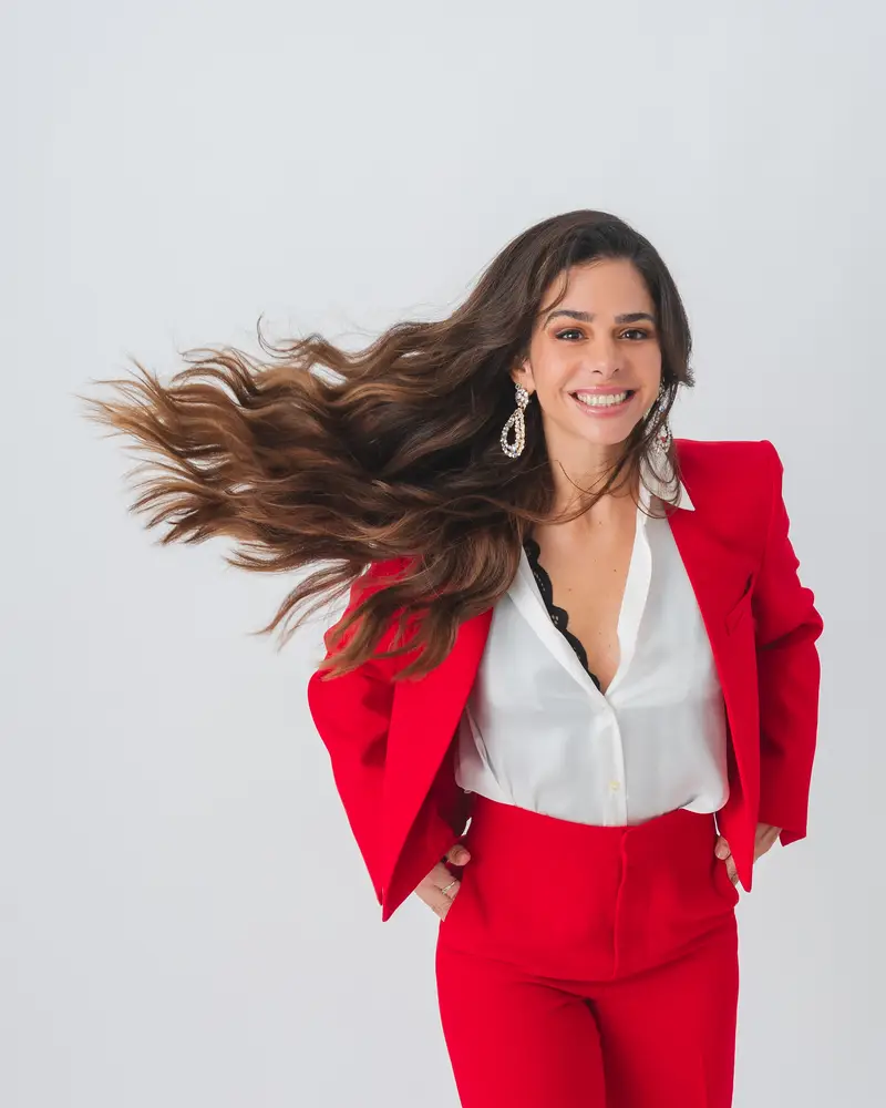 Priscilla Jorge de terno vermelho, com o cabelo em movimento